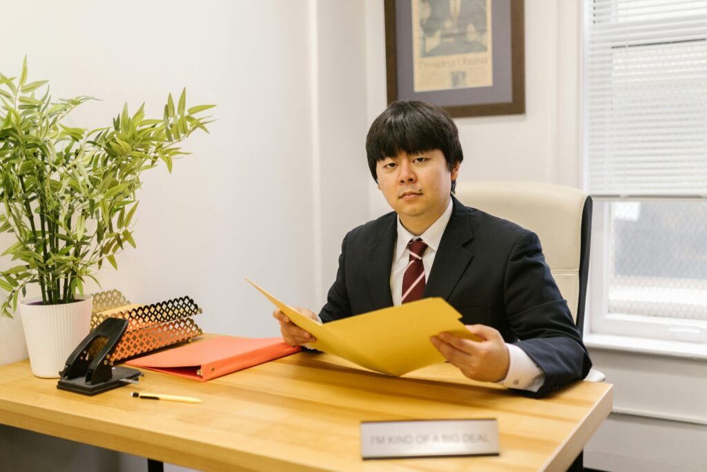 Asian businessman holding a folder in a modern office setting.